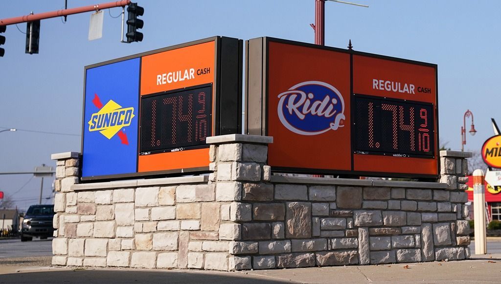 Gas station price sign with blue, orange, and white logos, displaying prices.