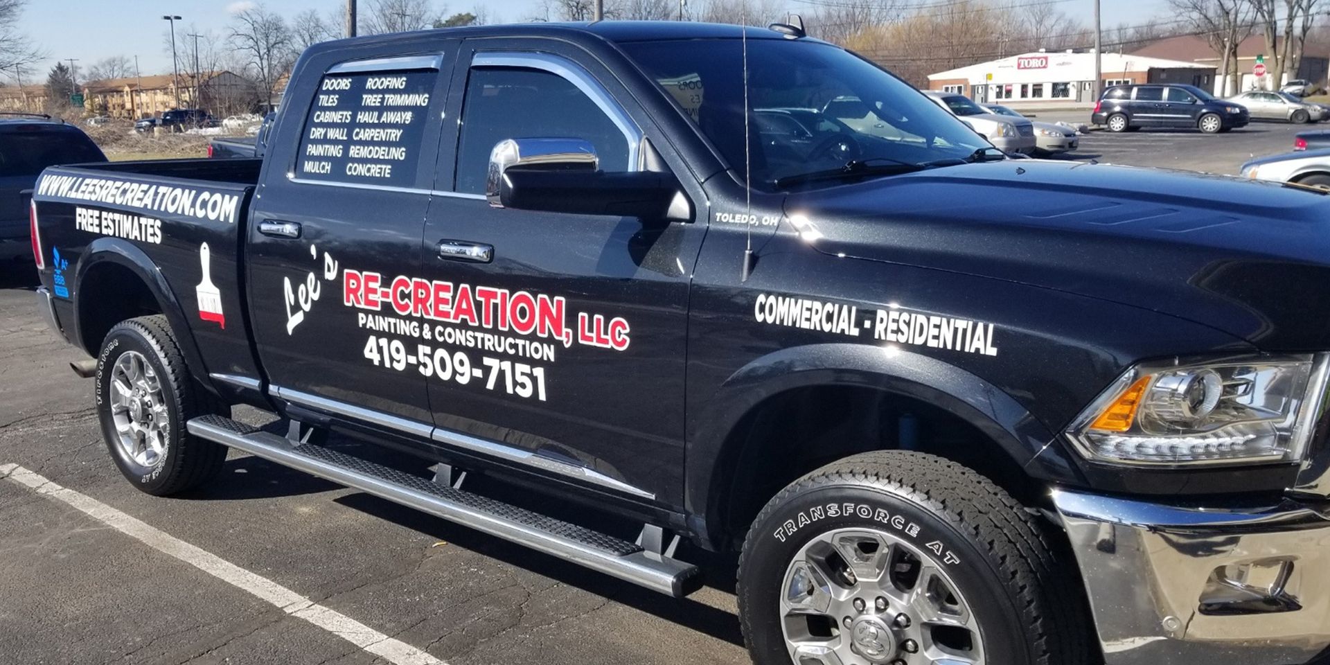 Black pickup truck with business logos parked outside.