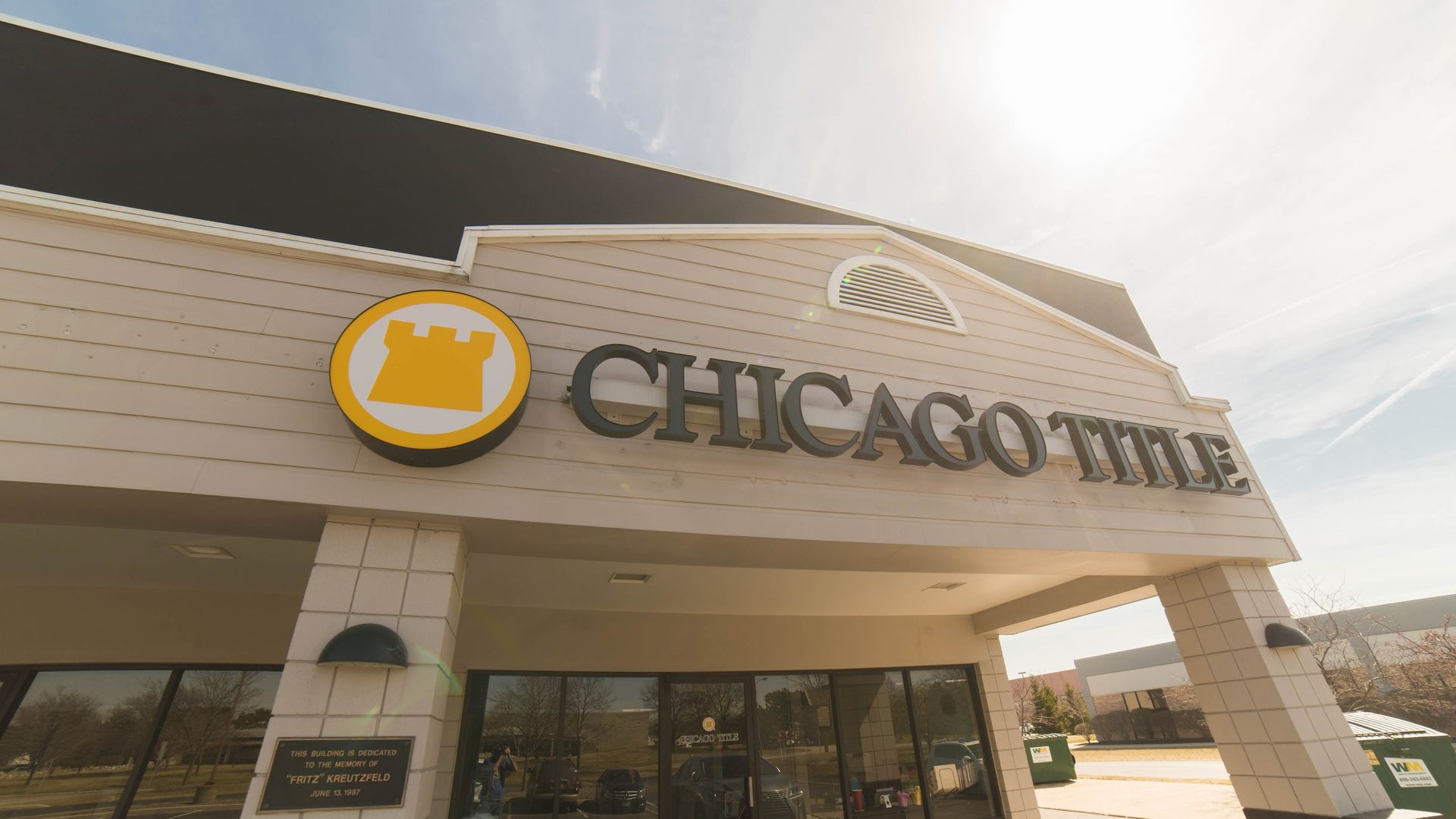 Chicago Title building with logo and entrance, under a bright sky.