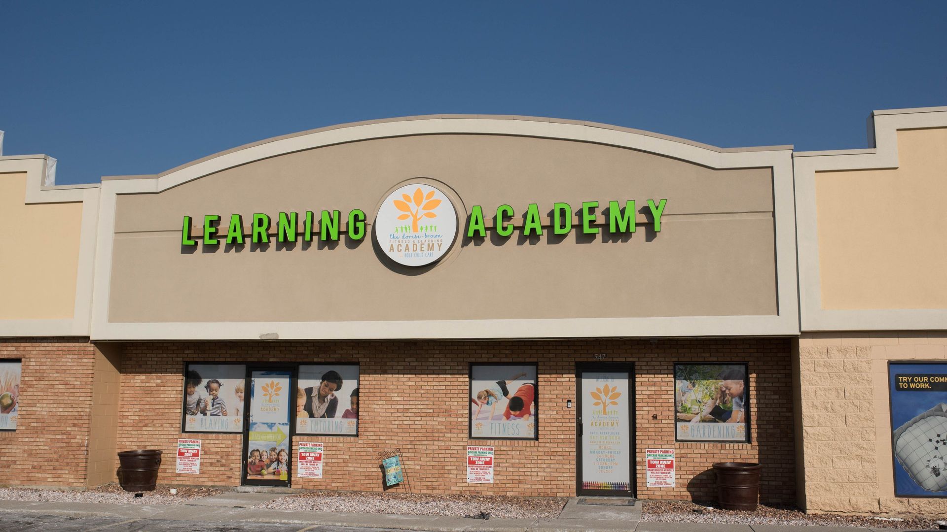 Exterior of Learning Academy building with green lettering and logo, blue sky.