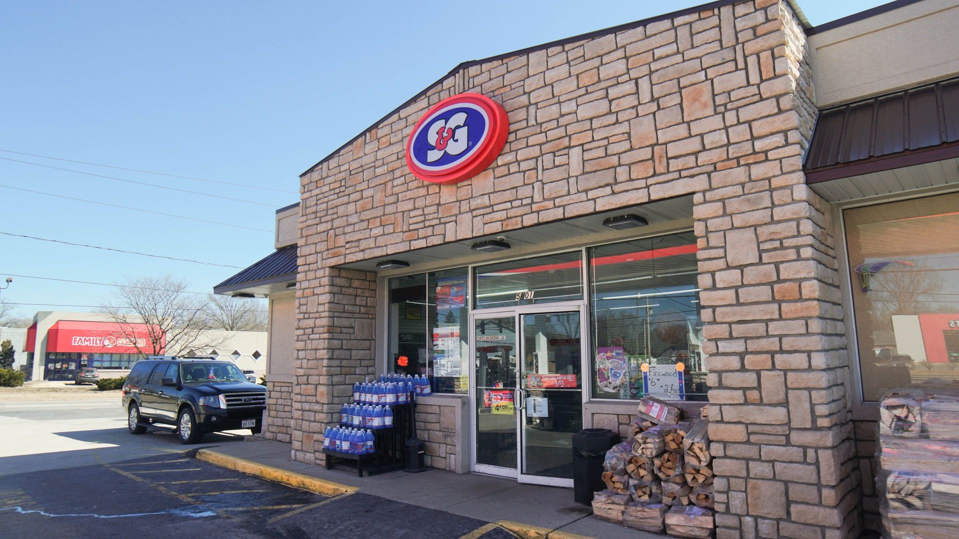 Gas station entrance with brick facade, blue sky, SUV, and C3 logo.