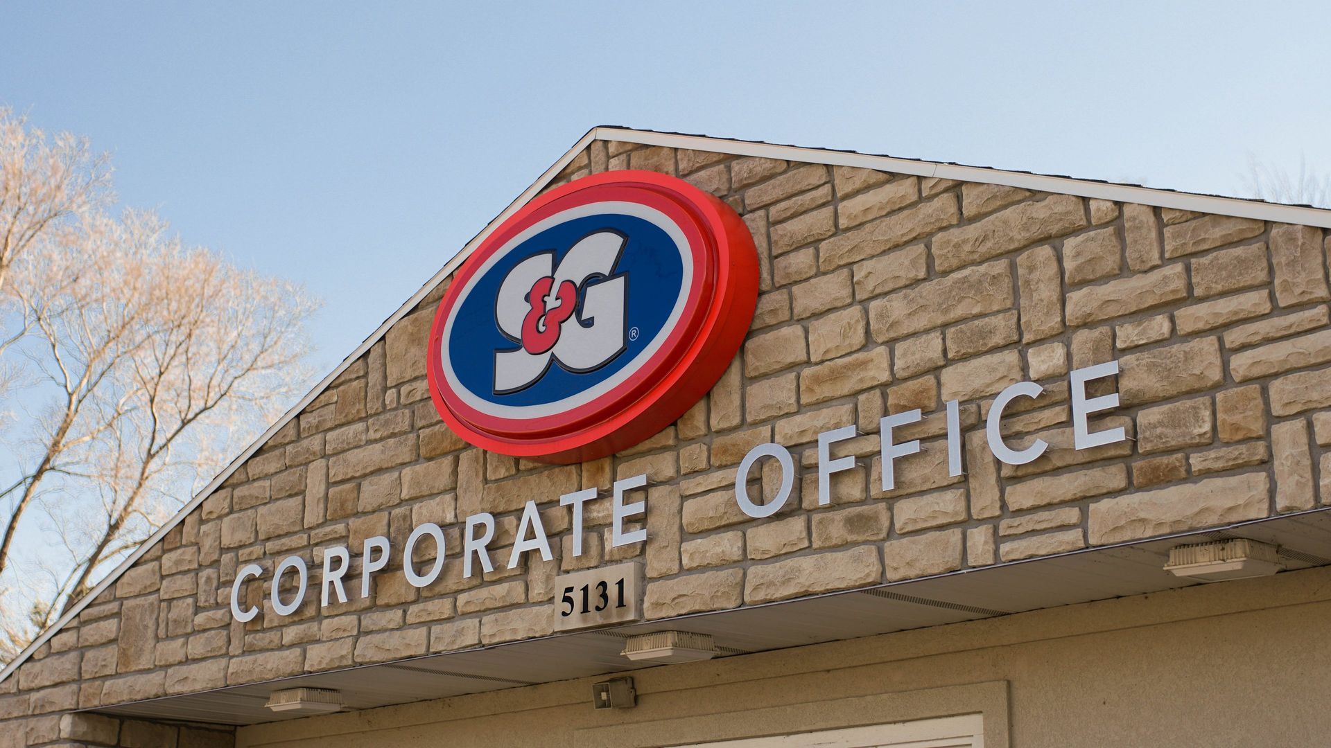 Corporate Office building with a red, white, and blue SG logo, set against a light brick facade.