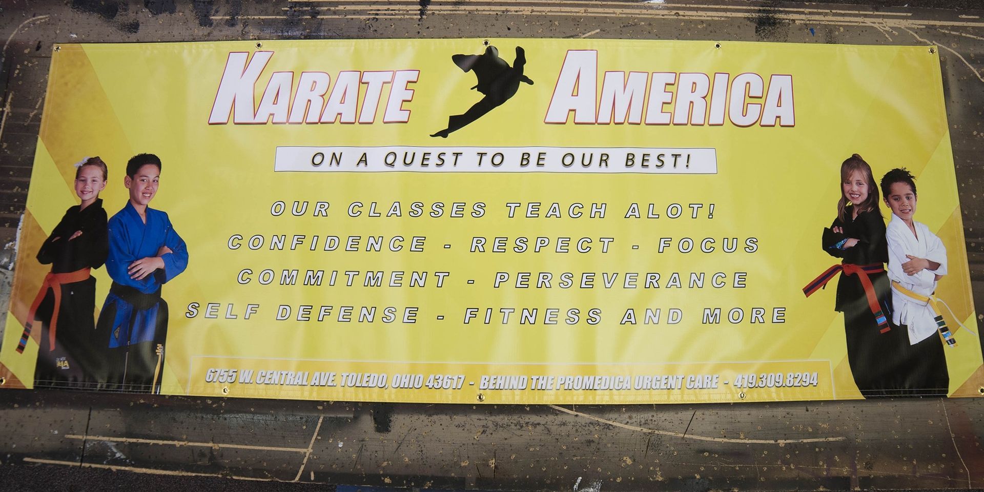 Karate America sign with children in karate uniforms. Yellow background, black and white text.