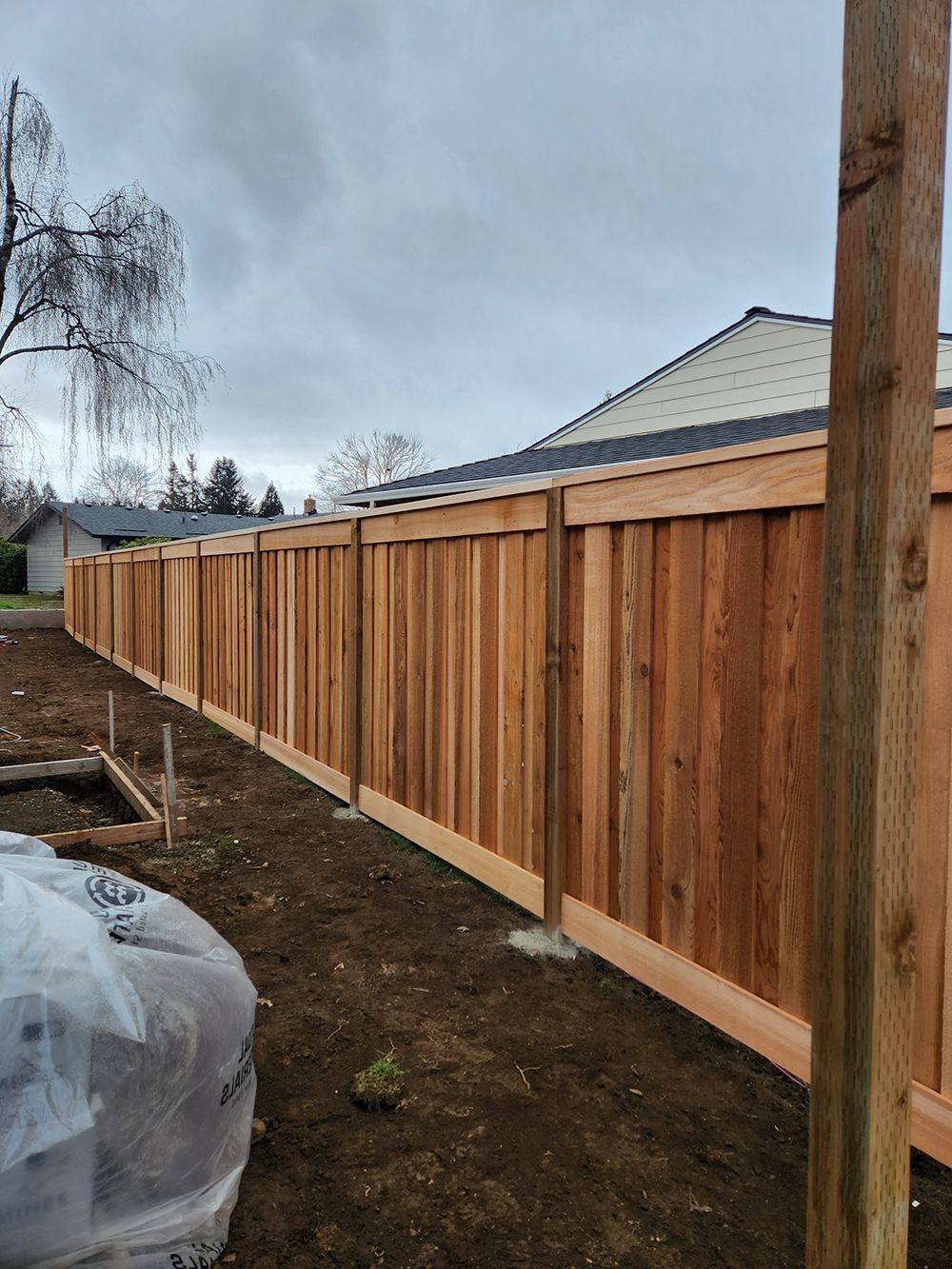 A wooden fence is being built in the backyard of a house