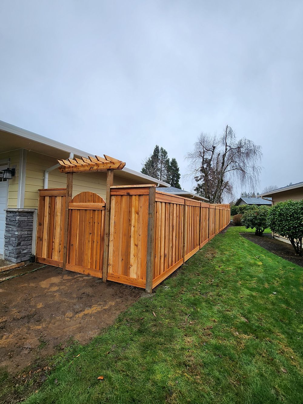 A wooden fence with a gate in the backyard of a house