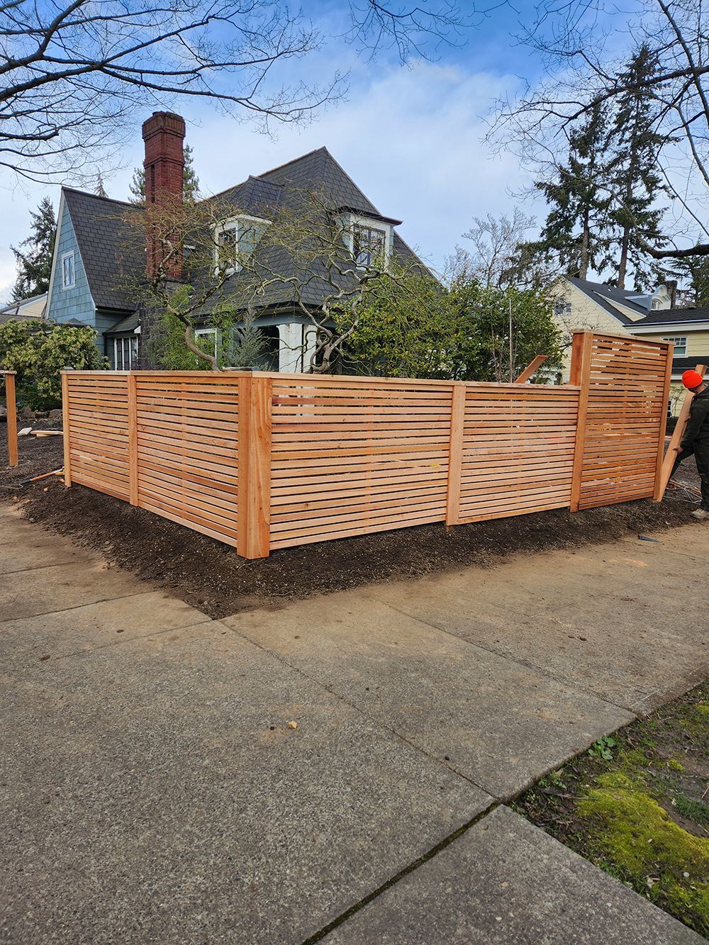 A wooden fence is sitting on the sidewalk in front of a house