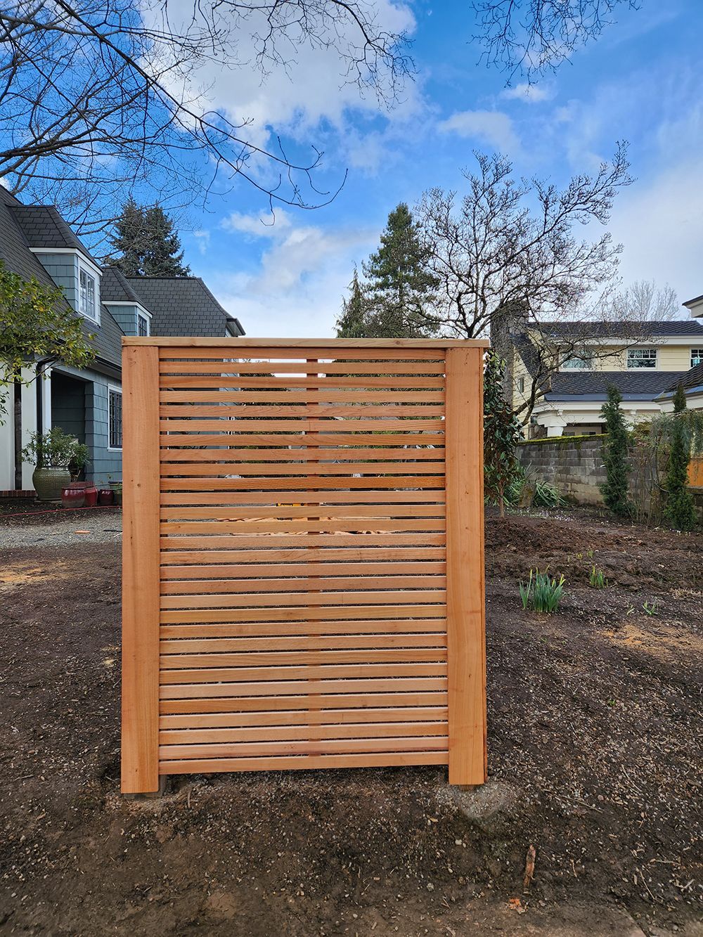 A wooden fence is sitting in the dirt in front of a house