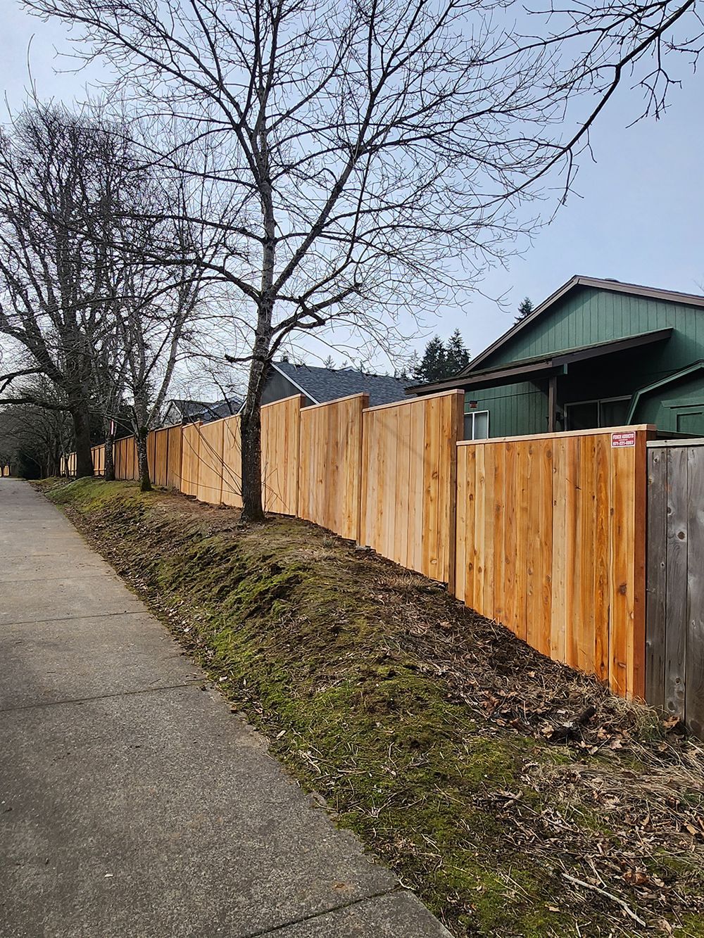 A wooden fence along a sidewalk next to a house