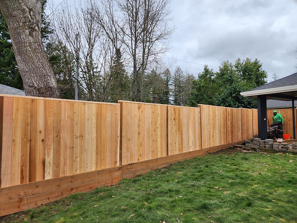 A wooden fence is being built in the backyard of a house