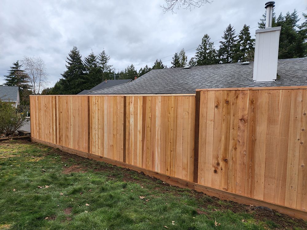A wooden fence is in the backyard of a house