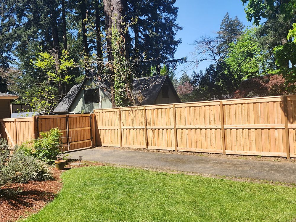 A wooden fence surrounds a lush green lawn in a backyard