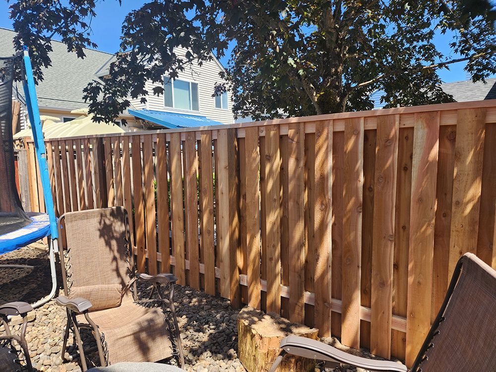 A wooden fence with chairs and a trampoline in the background