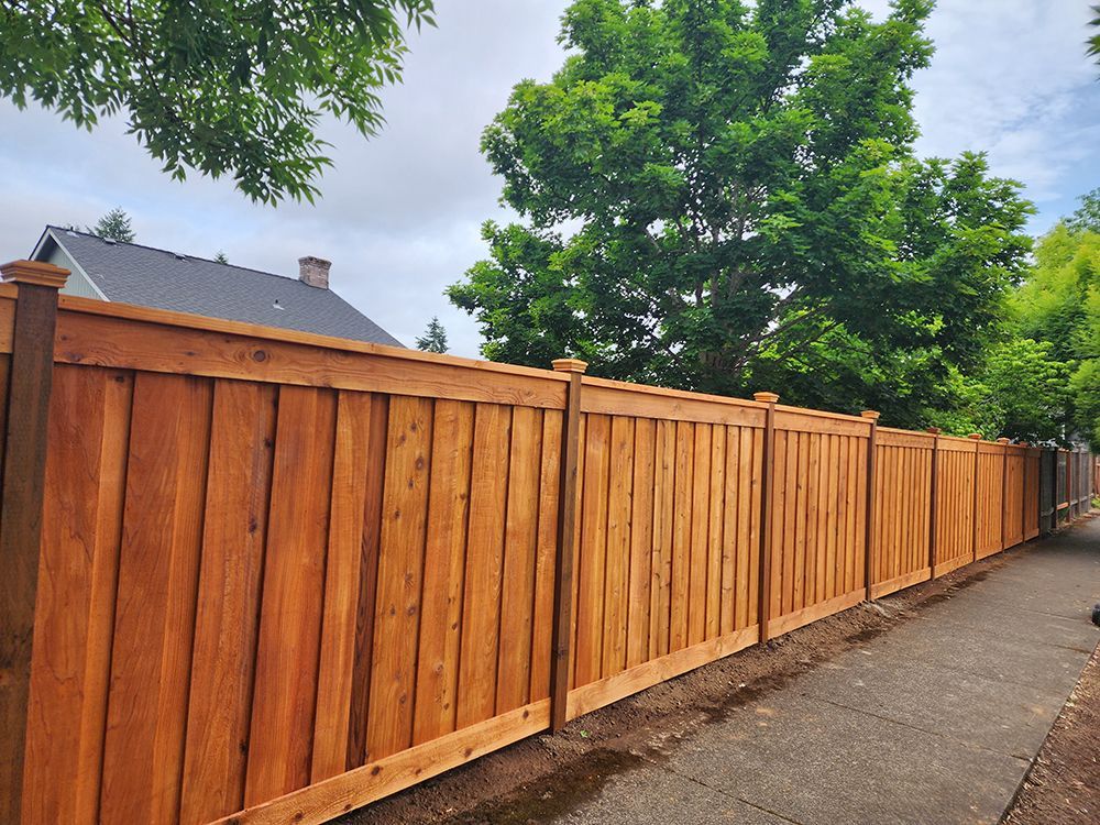 A wooden fence along a sidewalk next to a house