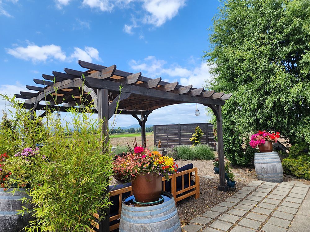 A wooden pergola with flowers in pots underneath it