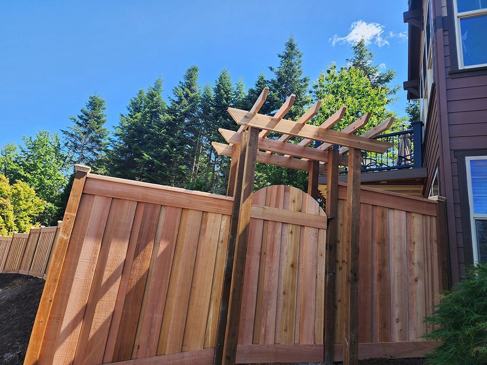 A wooden fence with a pergola attached to it in front of a house