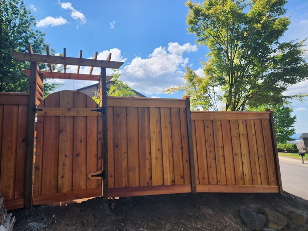 A wooden fence with a gate and a pergola attached to it