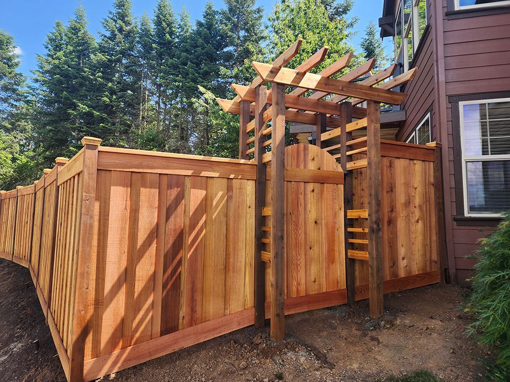 A wooden fence with a pergola attached to it is in front of a house