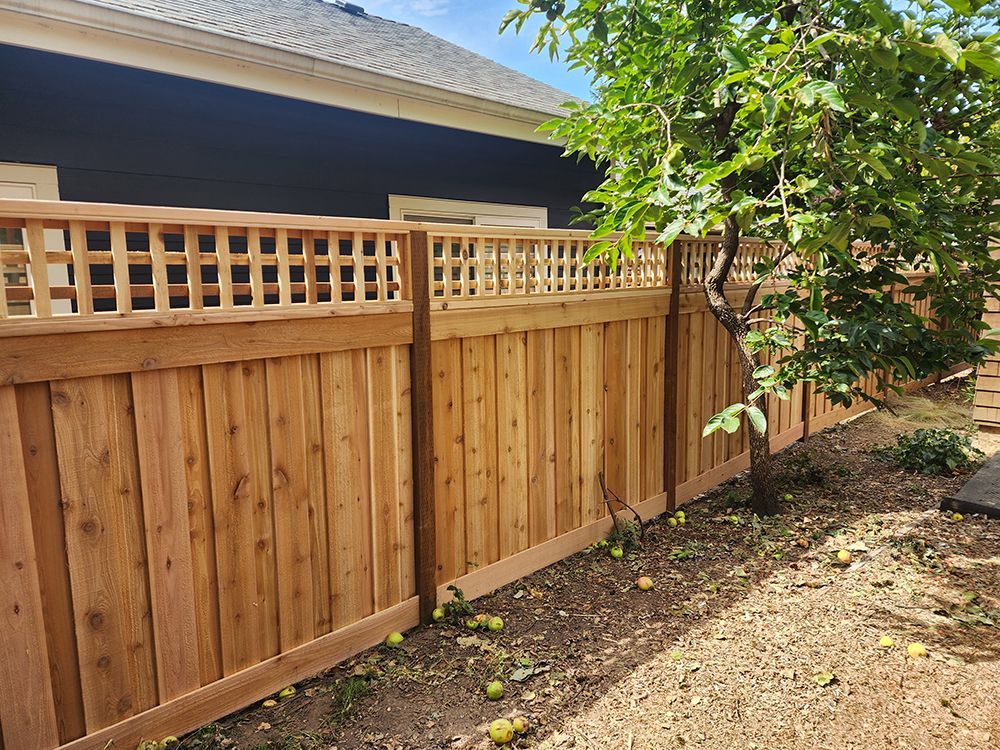 A wooden fence with a lattice design is in the backyard of a house