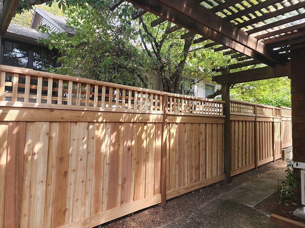 A wooden fence is surrounded by trees and a pergola