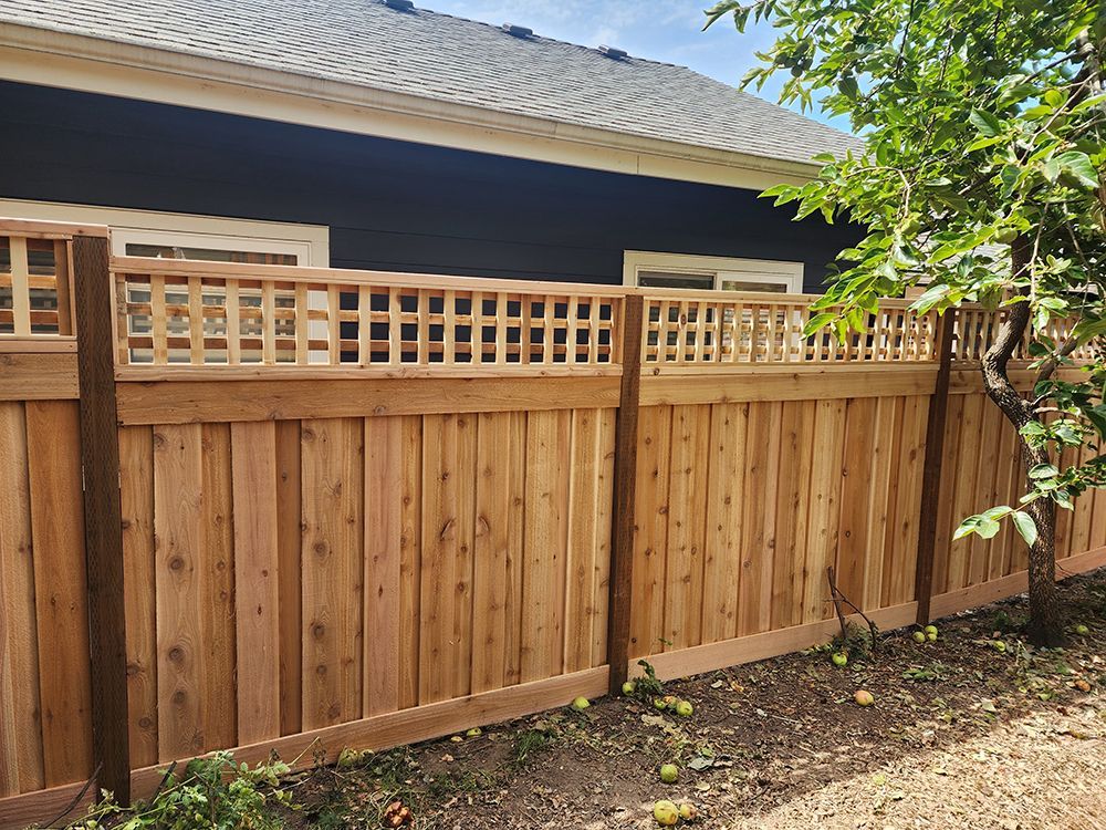 A wooden fence with a lattice top is in front of a house