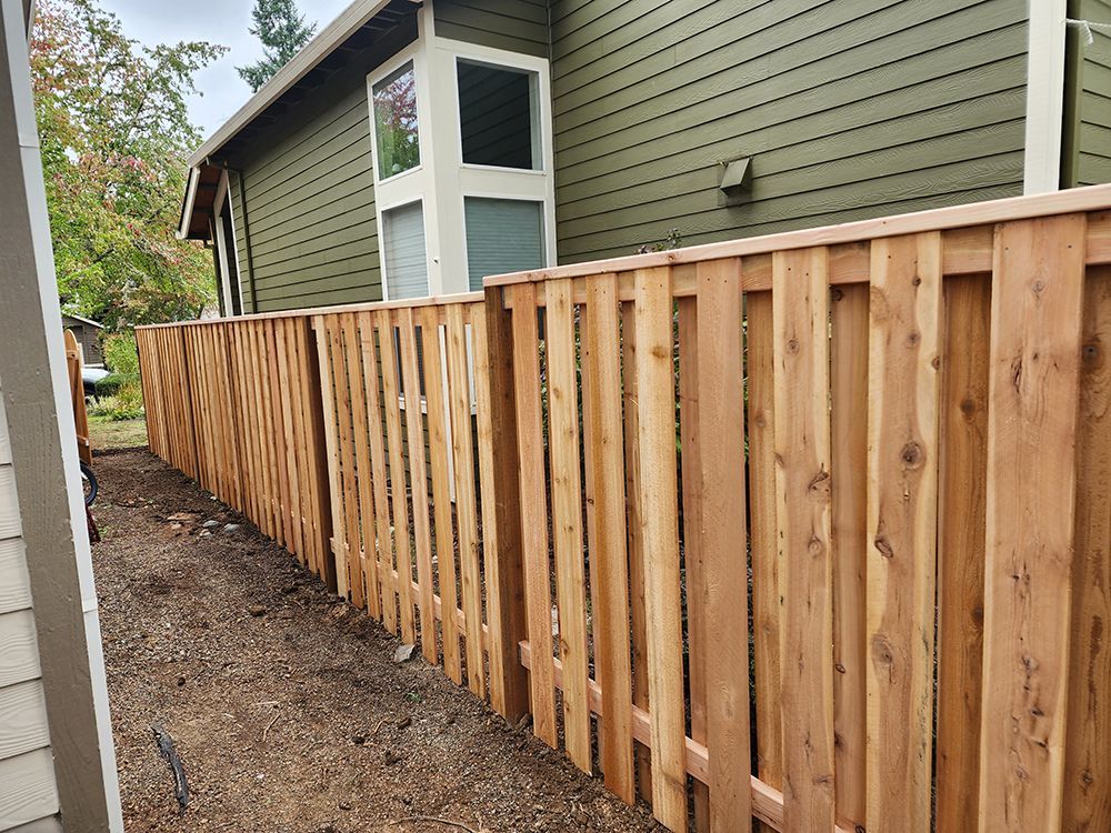 A wooden fence is sitting in front of a green house
