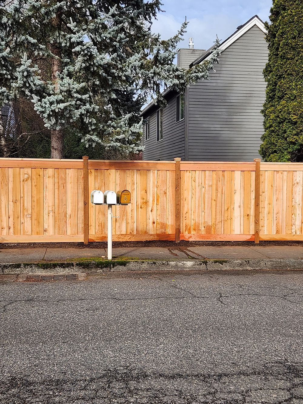 A wooden fence with a mailbox in front of a house