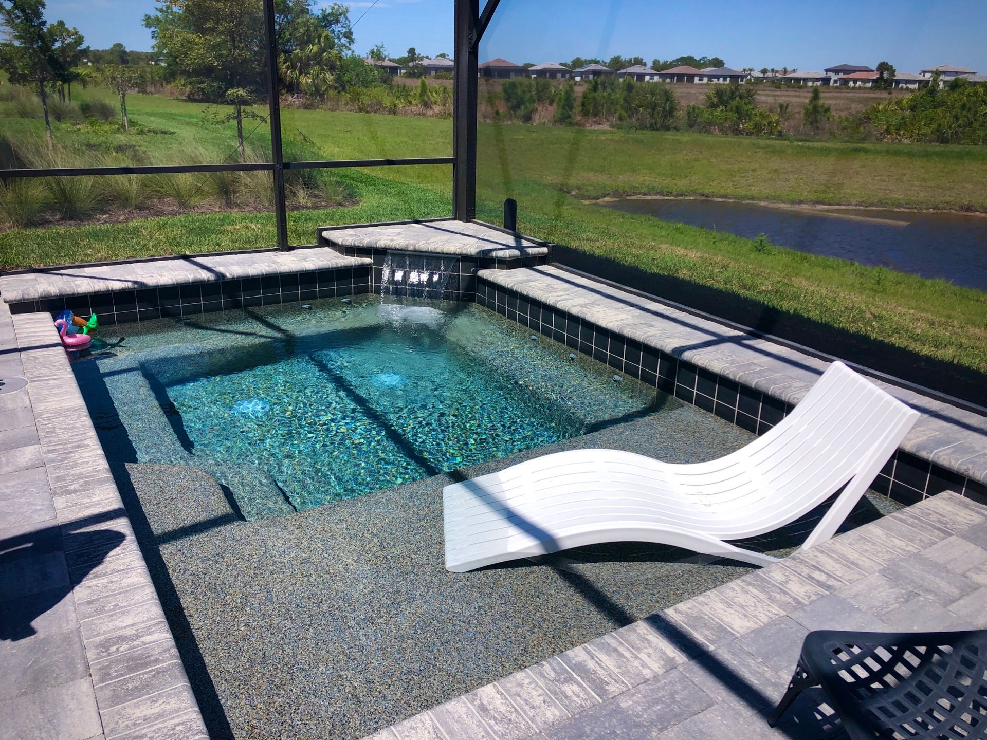A white lounge chair is sitting next to a swimming pool.