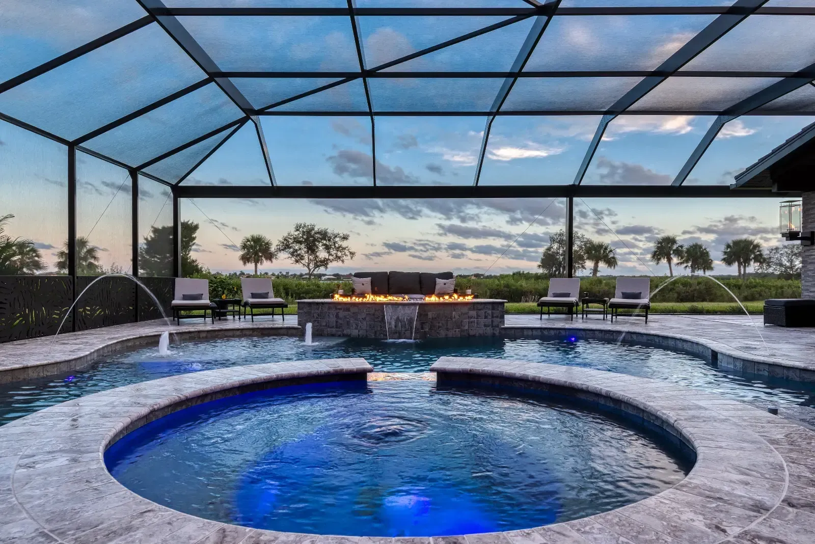 There is a large swimming pool with a fire pit in the middle of it.