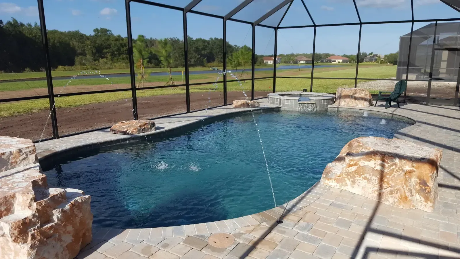 A large swimming pool is surrounded by a screened in area.