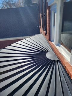 Sunburst pattern metal roofing against a brick wall and window.