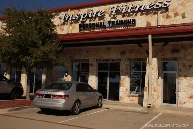 Silver car parked in front of Inspire Fitness, a personal training studio, in a stone building.