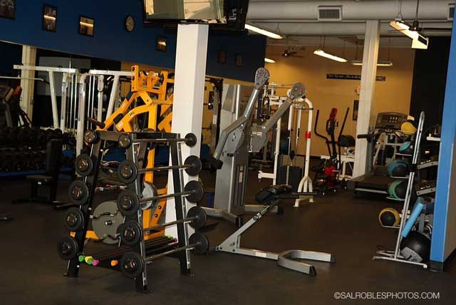 Gym interior with weight racks, exercise machines, and equipment.