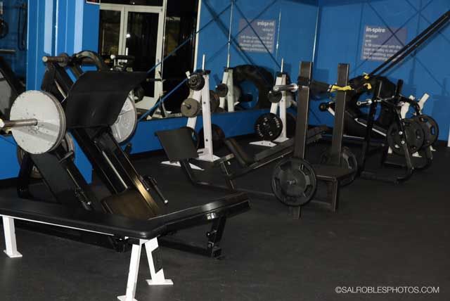 Weight machines in a gym, with blue walls and black equipment.