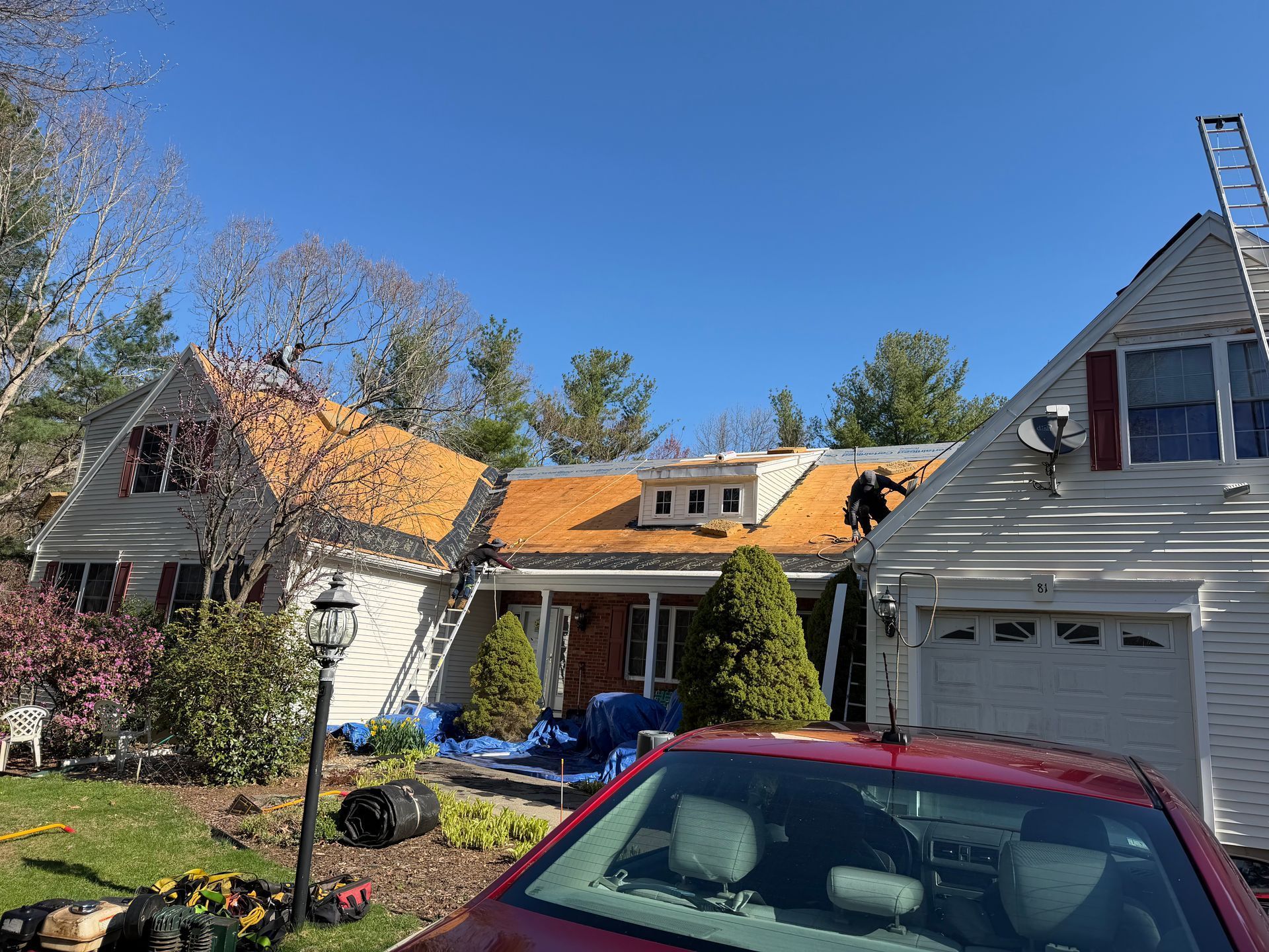 Suburban houses with orange roofs and a red car parked in the driveway under a blue sky
