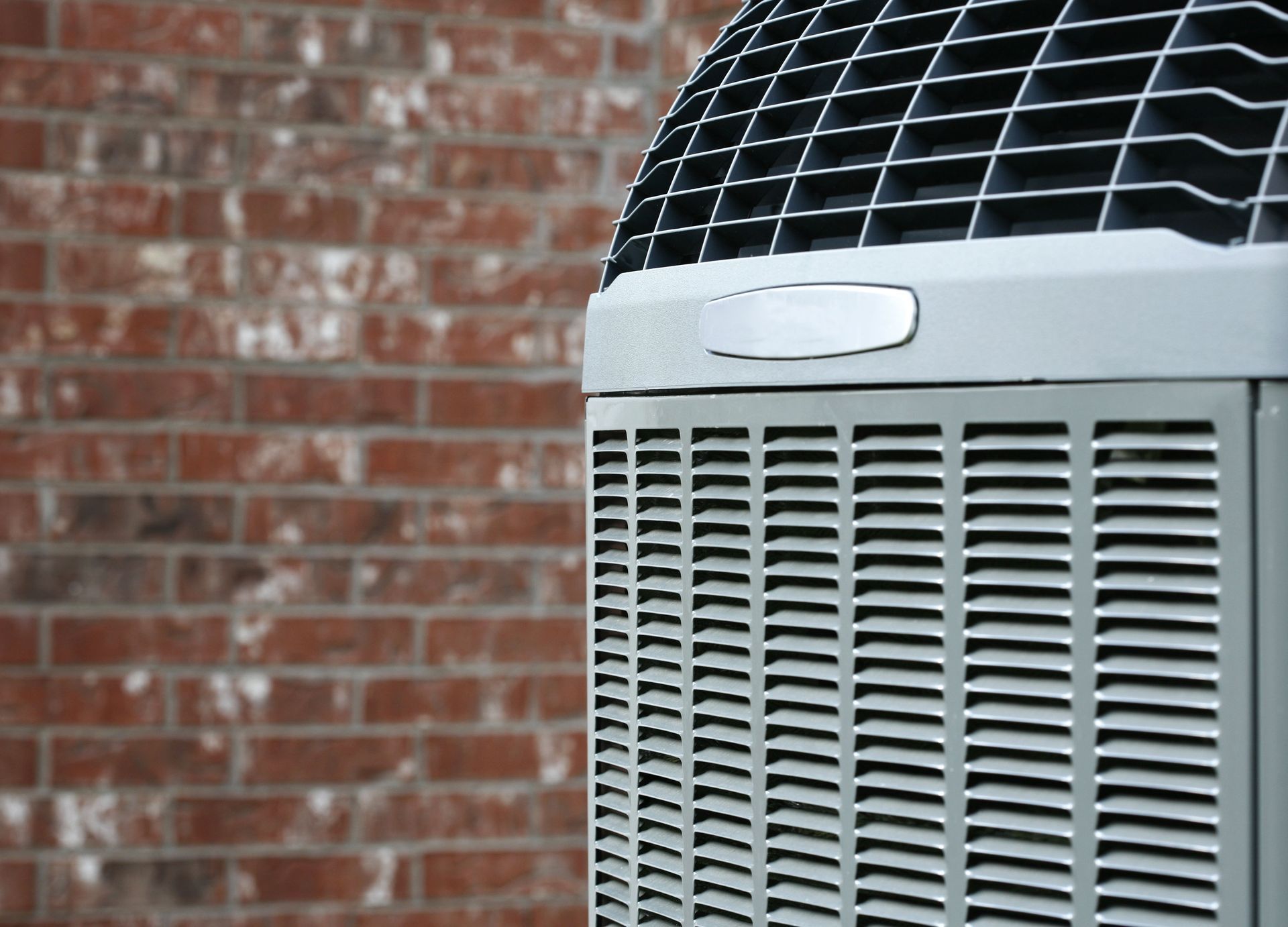 Outdoor air conditioner unit beside a red brick wall