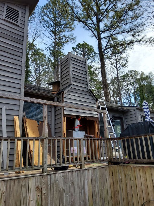 A wooden chimney is being installed on the side of a house.
