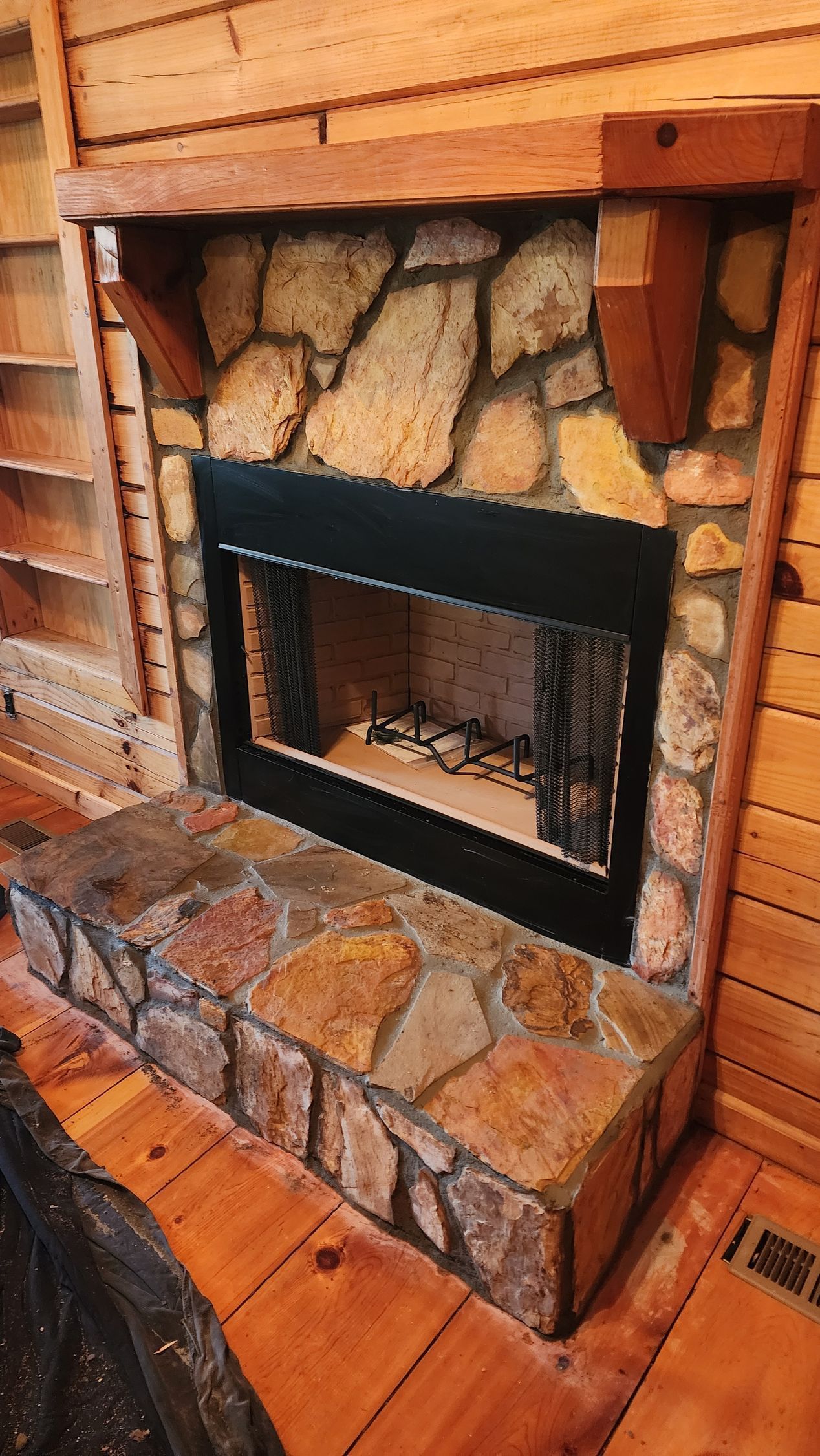 A stone fireplace with a wooden mantle in a living room.