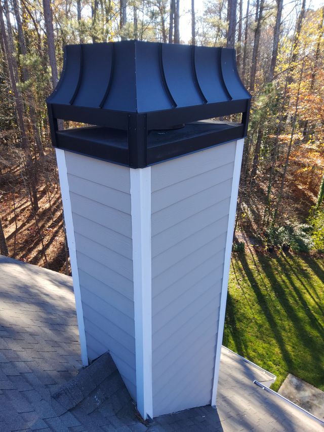A chimney on top of a roof with trees in the background