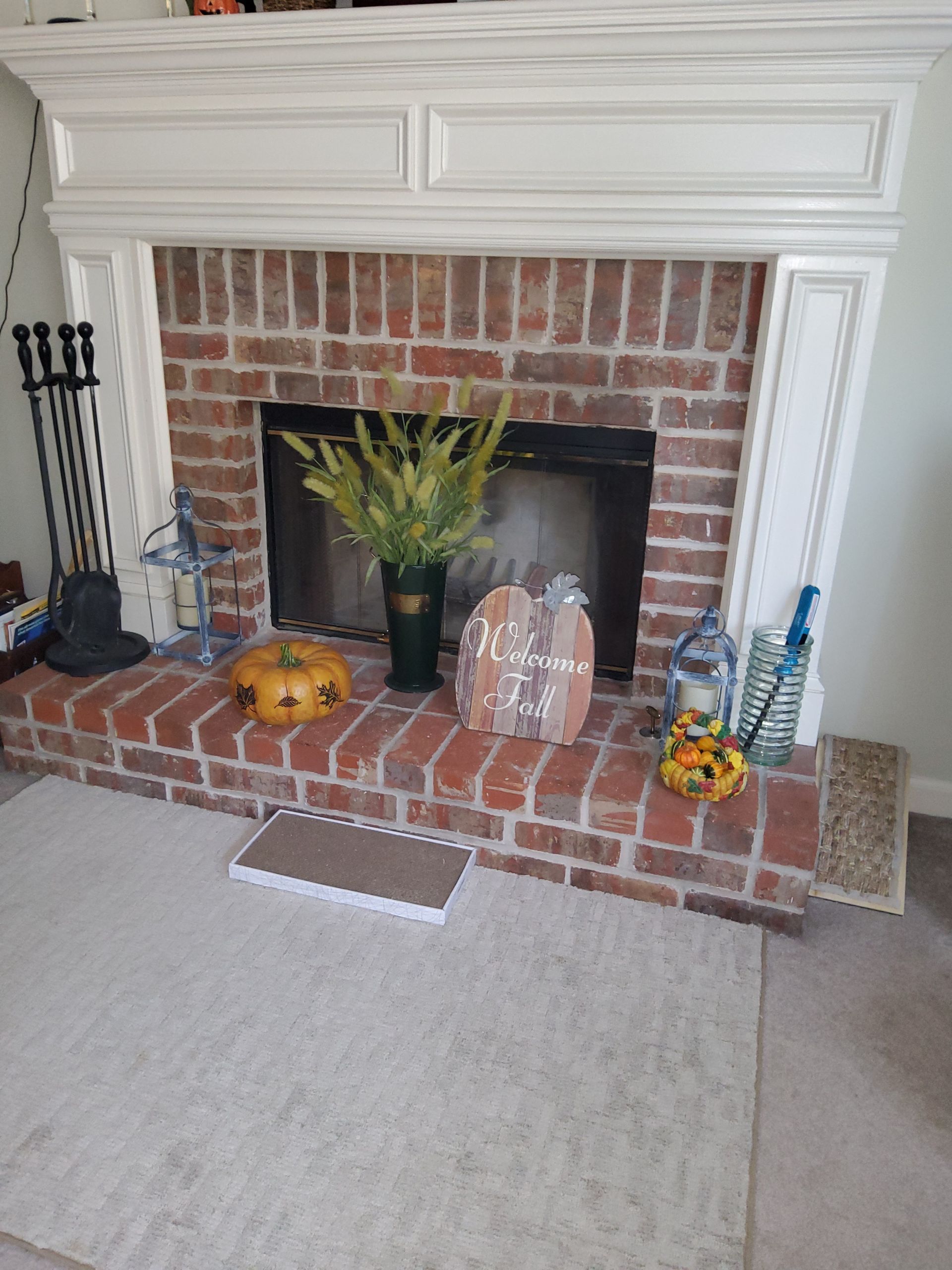A living room with a brick fireplace and a white mantle.