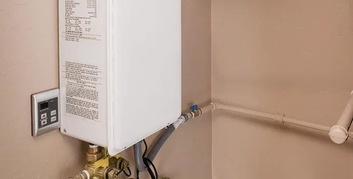 A white water heater is attached to a wall in a room.