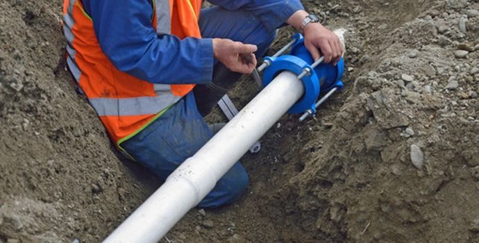 A group of men are working on a pipe in the ground.