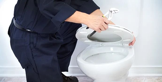 A man is cleaning a toilet with a plunger.
