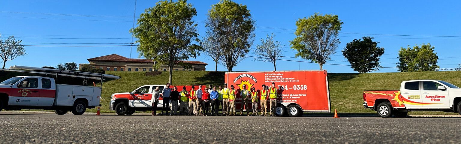 Firefighters stand near trucks and a trailer under a blue sky.