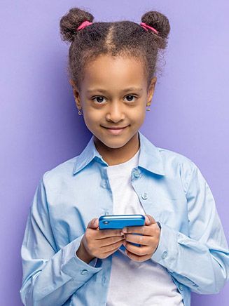 Girl holding a blue phone, smiling in front of a purple wall.