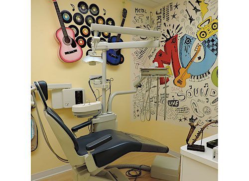 Dental office room with guitar decorations and equipment; a patient chair is in the foreground.