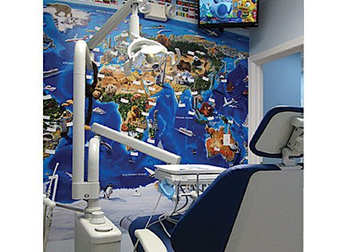 Dental office with a blue chair, equipment, and a world map mural.