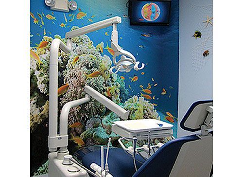 Dental office with blue chair and underwater mural; dental light and TV.