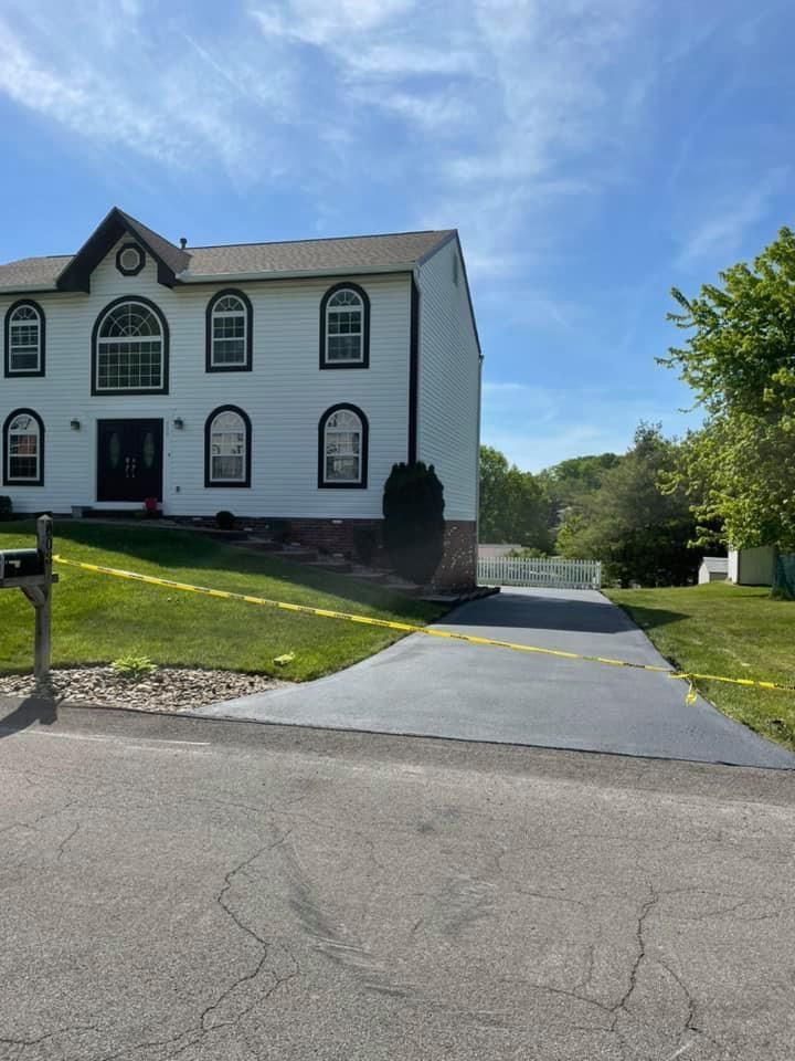A large white house with a concrete driveway in front of it.