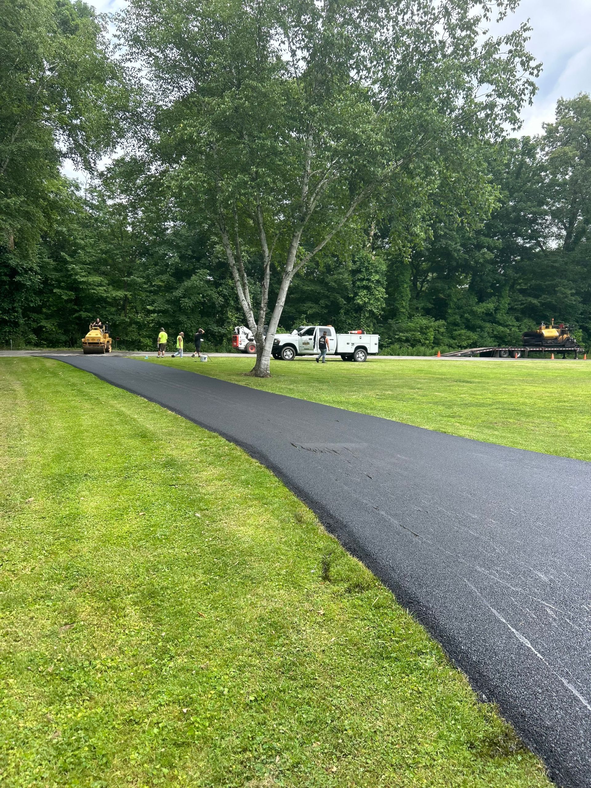 A road is being paved in a grassy field.