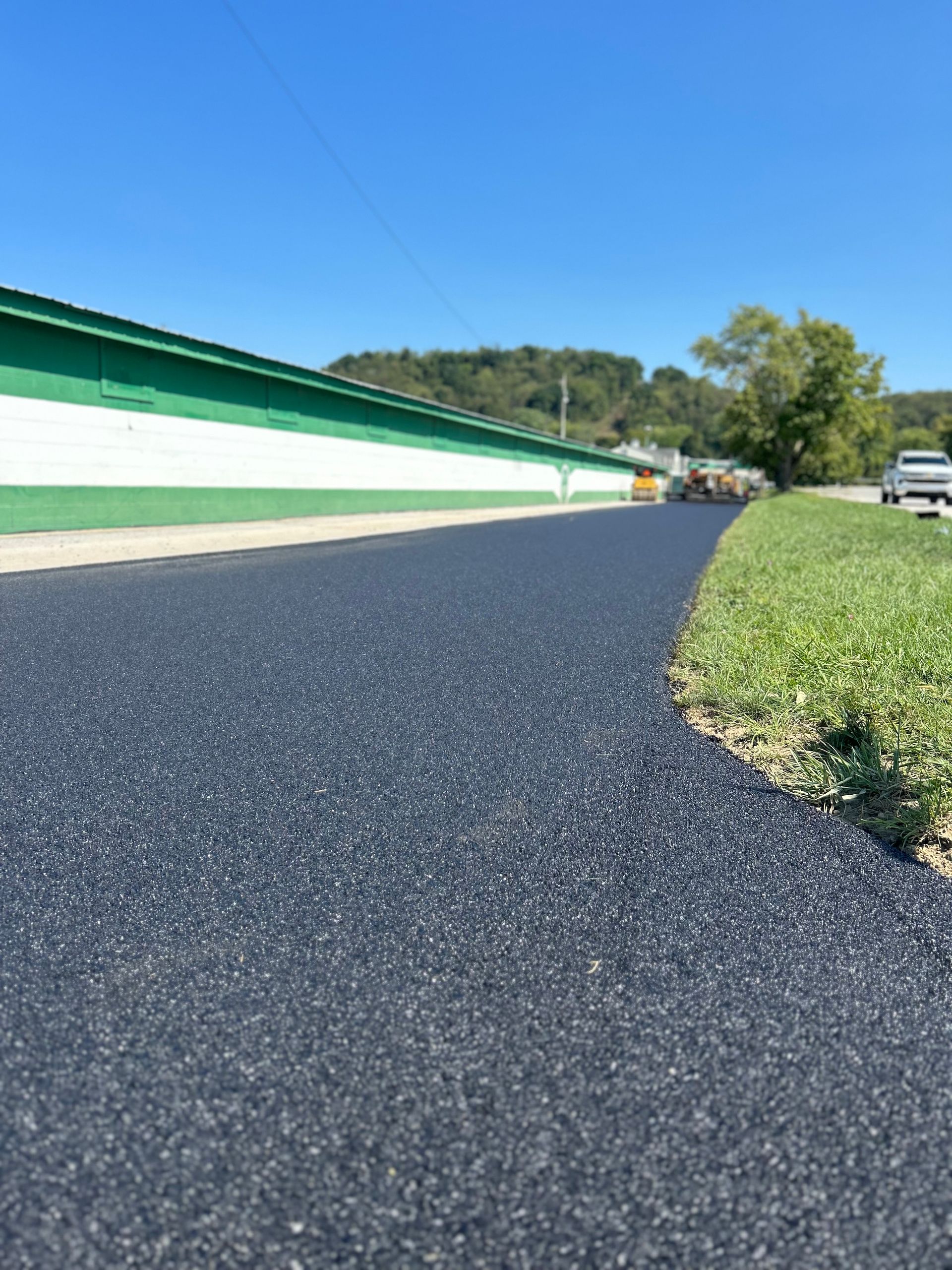 A road with a green and white building on the side of it.